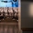 A dimly lit display features statues of athletes standing on a podium. They are positioned in front of a backdrop with the words 'LEVELING THE PLAYING FIELD' in bold letters. On the wall to the right, a softly lit quote is partially visible. The overall ambiance suggests a museum or exhibition setting.